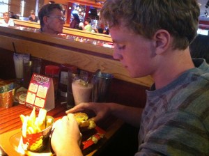 The boy is eating a BURGER with an EGG on it. Ugh. 